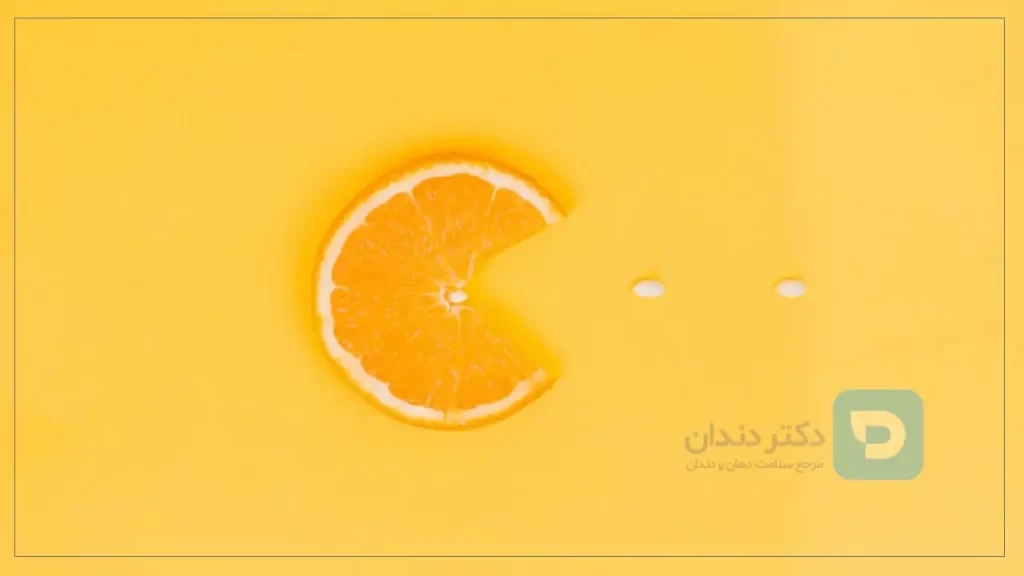 تصویر یک برش پرتقال و چند قرص ویتامین c برای رفع زردی دندان ها