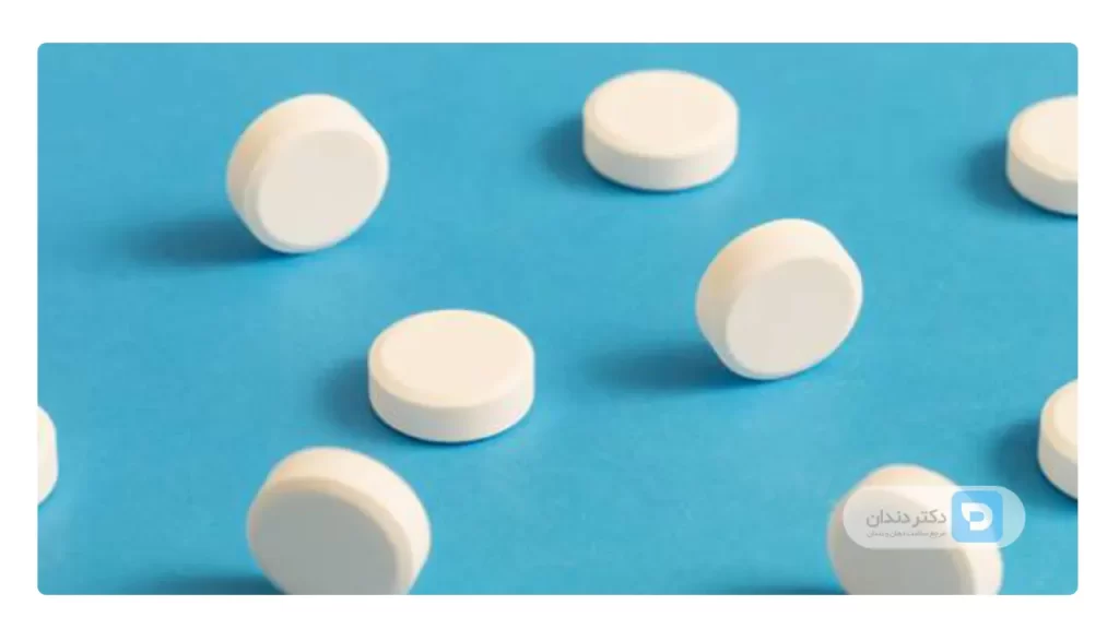 قرص های سفید ایبوپروفن  روی یک میز ابی رنگ
